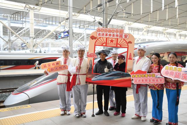 (251226) -- XI'AN, Dec. 26, 2025 (Xinhua) -- Passengers taking the first train of the Xi'an-Yan'an high-speed railway pose for photos with performers at Yan'an Station in Yan'an, northwest China's Shaanxi Province, Dec. 26, 2025. A sleek silver bullet train departed Yan'an in northwest China's Shaanxi Province on Friday, linking the sacred revolutionary heartland to the country's rapidly expanding high-speed rail network.
   The newly opened 299-km line connects Yan'an with Xi'an, the provincial capital and home to the famed Terracotta Warriors, slashing travel time between the two cities from about 2.5 hours to roughly one hour.
   Designed for operations of up to 350 km per hour, the line marked the fastest train running on the Loess Plateau. (Xinhua/Zhang Bowen)