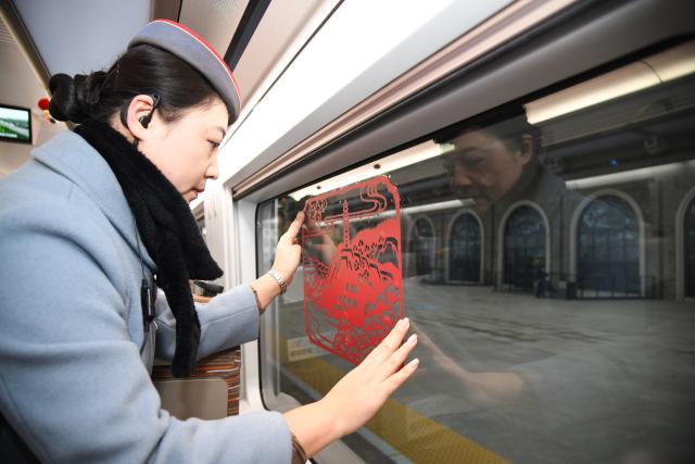 (251226) -- XI'AN, Dec. 26, 2025 (Xinhua) -- A train attendant pastes a paper-cut window decoration on the first train of the Xi'an-Yan'an high-speed railway at Yan'an Station in Yan'an, northwest China's Shaanxi Province, Dec. 26, 2025. A sleek silver bullet train departed Yan'an in northwest China's Shaanxi Province on Friday, linking the sacred revolutionary heartland to the country's rapidly expanding high-speed rail network.
   The newly opened 299-km line connects Yan'an with Xi'an, the provincial capital and home to the famed Terracotta Warriors, slashing travel time between the two cities from about 2.5 hours to roughly one hour.
   Designed for operations of up to 350 km per hour, the line marked the fastest train running on the Loess Plateau. (Xinhua/Zhang Bowen)