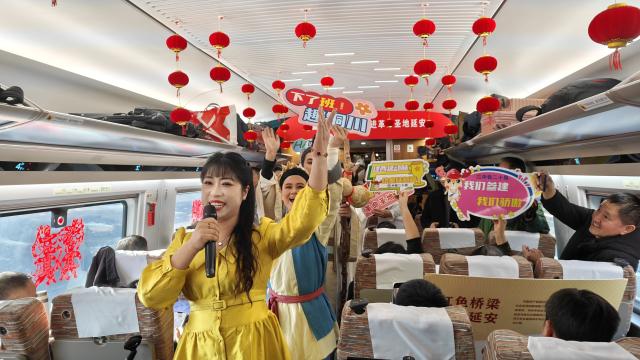 (251226) -- XI'AN, Dec. 26, 2025 (Xinhua) -- People perform on the first train of the Xi'an-Yan'an high-speed railway in northwest China's Shaanxi Province, Dec. 26, 2025. A sleek silver bullet train departed Yan'an in northwest China's Shaanxi Province on Friday, linking the sacred revolutionary heartland to the country's rapidly expanding high-speed rail network.
   The newly opened 299-km line connects Yan'an with Xi'an, the provincial capital and home to the famed Terracotta Warriors, slashing travel time between the two cities from about 2.5 hours to roughly one hour.
   Designed for operations of up to 350 km per hour, the line marked the fastest train running on the Loess Plateau. (Xinhua/Xing Guangli)