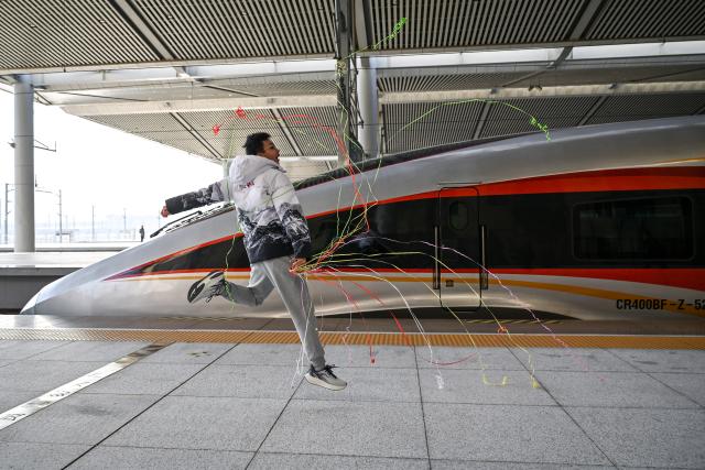 (251226) -- XI'AN, Dec. 26, 2025 (Xinhua) -- A passenger celebrates in front of C9312, the first train of the Xi'an-Yan'an high-speed railway, at Xi'an North Railway Station in northwest China's Shaanxi Province, on Dec. 26, 2025. A sleek silver bullet train departed Yan'an in northwest China's Shaanxi Province on Friday, linking the sacred revolutionary heartland to the country's rapidly expanding high-speed rail network.
   The newly opened 299-km line connects Yan'an with Xi'an, the provincial capital and home to the famed Terracotta Warriors, slashing travel time between the two cities from about 2.5 hours to roughly one hour.
   Designed for operations of up to 350 km per hour, the line marked the fastest train running on the Loess Plateau. (Xinhua/Zou Jingyi)