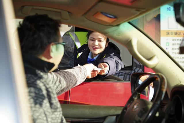 (251226) -- URUMQI, Dec. 26, 2025 (Xinhua) -- A staff member (R) hands a passing card to a driver at a toll station for the Urumqi-Yuli Expressway in northwest China's Xinjiang Uygur Autonomous Region, Dec. 26, 2025. The 22.13-km Tianshan Shengli Tunnel, the world's longest expressway tunnel, officially opened to traffic on Friday.
   Traversing the central Tianshan Mountains in northwest China's Xinjiang Uygur Autonomous Region, the tunnel slashes what was once a several-hour mountain drive to just 20 minutes.
   As a vital artery linking city clusters in northern and southern Xinjiang, the G0711 Urumqi-Yuli Expressway, including the tunnel, entered operation on the same day. (Xinhua/Xu Hongyan)