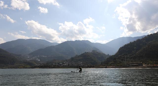 (251226) -- NANJIAN, Dec. 26, 2025 (Xinhua) -- A man experiences paddle boarding at a water sports base on the Lancang River in Gonglang Town in Nanjian Yi Autonomous County, southwest China's Yunnan Province, Dec. 25, 2025. In recent years, Gonglang Town, boasting an advantageous ecological environment and pleasant climate throughout the year, has actively revitalized the rural economy by developing water sports initiatives and promoting cultural tourism.
   The town has established competitive, training, and experiential settings for a diverse range of open-water sports, and has proactively sought to host sports events and training programs. Additionally, it provides a host of cultural and tourism services, including catering and travel photography. These concerted efforts have created employment opportunities and diversified income sources for local villagers. (Xinhua/Du Xiaoyi)