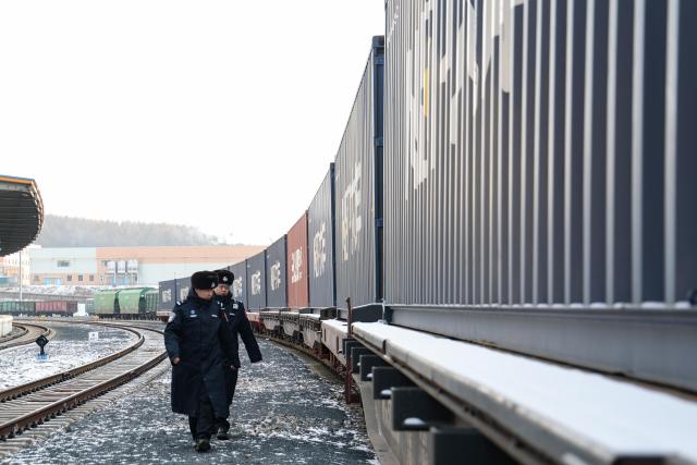 (251226) -- SUIFENHE, Dec. 26, 2025 (Xinhua) -- Police officers inspect a China-Europe freight train at the south yard of Suifenhe Railway Station in Suifenhe, northeast China's Heilongjiang Province, on Dec. 25, 2025. As a vital part of the eastern corridor of the China-Europe freight train network, the Suifenhe Railway Port has handled more than 4,000 China-Europe freight train trips since its launch in 2018, carrying over 390,000 TEUs of cargo, according to data from China Railway Harbin Group Co., Ltd. (Photo by Qu Yiwei/Xinhua)