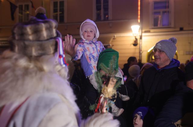 (251226) -- LJUBLJANA, Dec. 26, 2025 (Xinhua) -- A man dressed as Grandpa Frost gives a high five to a child during a procession on the Presernov Square in Ljubljana, Slovenia, Dec. 26, 2025. (Photo by Zeljko Stevanic/Xinhua)