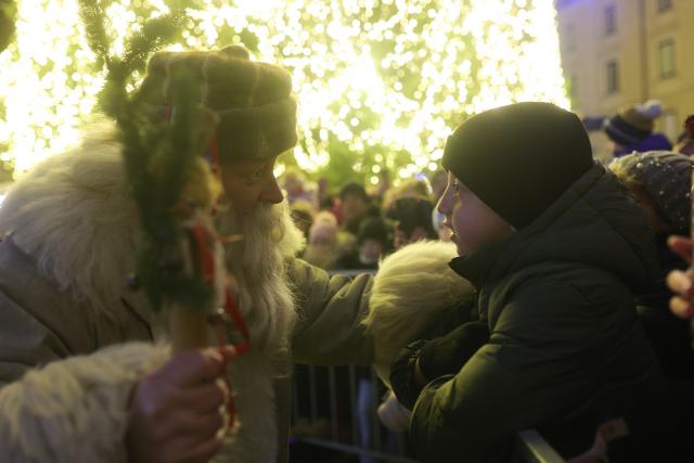 (251226) -- LJUBLJANA, Dec. 26, 2025 (Xinhua) -- A man dressed as Grandpa Frost interacts with a child during a procession on the Presernov Square in Ljubljana, Slovenia, Dec. 26, 2025. (Photo by Zeljko Stevanic/Xinhua)