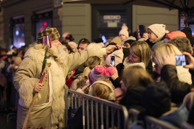 (251226) -- LJUBLJANA, Dec. 26, 2025 (Xinhua) -- A man dressed as Grandpa Frost offers sweets to children during a procession on the Presernov Square in Ljubljana, Slovenia, Dec. 26, 2025. (Photo by Zeljko Stevanic/Xinhua)