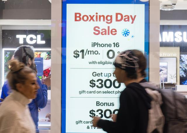 (251226) -- TORONTO, Dec. 26, 2025 (Xinhua) -- People walk past a Boxing Day promotion sign in Toronto, Canada, on Dec. 26, 2025. (Photo by Zou Zheng/Xinhua)