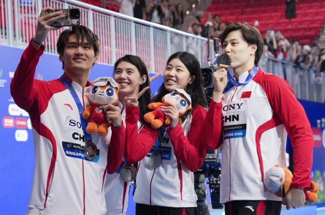 (251227) -- BEIJING, Dec. 27, 2025 (Xinhua) -- Here is Xinhua News Agency's selection of the 10 most significant pieces of Chinese sports news in 2025: At the World Aquatics Championships held in Singapore from July 11 to August 3, China claimed 15 gold, 12 silver and 10 bronze medals in artistic swimming, diving and swimming, retaining its top positions in both the gold medal table and overall medal standings.
This file photo taken on July 30, 2025 shows team China's Xu Jiayu, Zhang Yufei, Wu Qingfeng and Qin Haiyang (L to R) taking selfies after the awarding ceremony for the mixed 4x100m medley relay event of swimming at the World Aquatics Championships in Singapore. (Xinhua/Wu Zhizun)