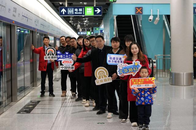 (251227) -- BEIJING, Dec. 27, 2025 (Xinhua) -- Constructors of Beijing Subway Line 18 pose for photos with their family members at Wenhualu Station of the line in Beijing, capital of China, Dec. 27, 2025. Beijing Subway Line 18 began operation on Saturday. (Xinhua/Xing Guangli)