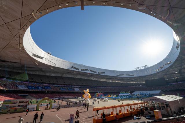 (251227) -- BEIJING, Dec. 27, 2025 (Xinhua) -- People play in the fashion and leisure zone at the National Stadium, also known as the Bird's Nest, in Beijing, capital of China, Dec. 27, 2025. The winter theme park of the Bird's Nest kicked off on Saturday and will run till late February 2026. The event features an ice and snow activity zone, and an outdoor fashion and leisure zone. (Xinhua/Xie Han)