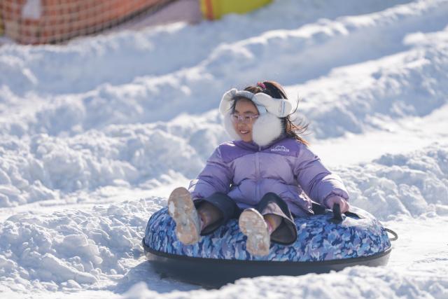 (251227) -- BEIJING, Dec. 27, 2025 (Xinhua) -- A child enjoys sliding on an inflatable snow sled outside the National Stadium, also known as the Bird's Nest, in Beijing, capital of China, Dec. 27, 2025. The winter theme park of the Bird's Nest kicked off on Saturday and will run till late February 2026. The event features an ice and snow activity zone, and an outdoor fashion and leisure zone. (Xinhua/Xie Han)