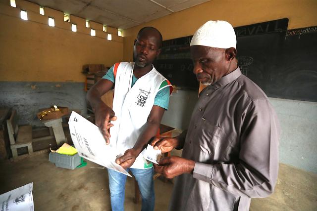 (251227) -- ABIDJAN, Dec. 27, 2025 (Xinhua) -- A staff member explains the voting rules to a voter at a polling station in Abidjan, Cote d'Ivoire, Dec. 27, 2025. Polling stations opened on Saturday morning across Cote d'Ivoire for legislative elections to renew the 255 seats of the National Assembly, Xinhua reporters observed on site in Abidjan, the country's economic capital.
TO GO WITH "Polling opens for legislative elections in Cote d'Ivoire " (Photo by Yvan Sonh/Xinhua)