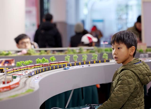 (251227) -- SHANGHAI, Dec. 27, 2025 (Xinhua) -- A boy visits a model train exhibition in Shanghai, east China, Dec. 27, 2025. The theme exhibition and related special activities were held at Shanghai Mass Art Center on Saturday. More than 50 model trains shuttled among ten theme scenes, presenting visitors with a wonderful miniature world about trains and railways. (Xinhua/Liu Ying)
