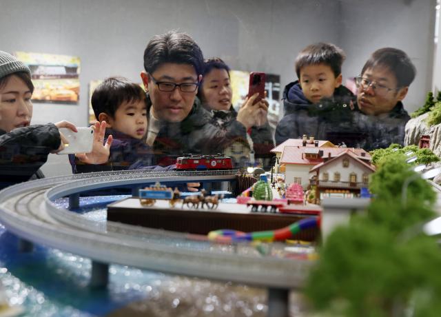 (251227) -- SHANGHAI, Dec. 27, 2025 (Xinhua) -- People visit a model train exhibition in Shanghai, east China, Dec. 27, 2025. The theme exhibition and related special activities were held at Shanghai Mass Art Center on Saturday. More than 50 model trains shuttled among ten theme scenes, presenting visitors with a wonderful miniature world about trains and railways. (Xinhua/Liu Ying)