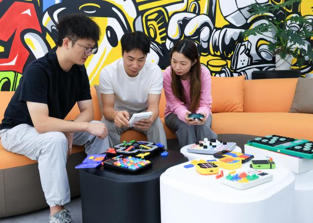 (251227) -- FOSHAN, Dec. 27, 2025 (Xinhua) -- Su Ziming (C), founder of Giiker, discusses the company's smart educational toy products with employees in Shunde, Foshan City, south China's Guangdong Province, Oct. 29, 2025. As traditional toys are stuck in price and homogenization competition, a batch of smart educational toys is quietly opening up new markets at home and abroad.
   In this emerging market segment, Giiker from Shunde of Foshan City, stands out. Founded in 2018, Giiker started with a Rubik's Cube product and has reached an annual gross merchandise volume of over 500 million yuan (about 71.36 million U.S. dollars) in just six years.
   Founder Su Ziming said that unlike the traditional toy industry's strategy of pursuing rapid launch and extensive distribution of new products, Giiker prefers to spend one to two years refining a product, emphasizing a long-term life cycle and high quality.
   Another outstanding company in this market segment is GANCUBE, a technology company also based in south China's Guangdong Province. It entered the market in 2014,  and has now developed into a smart competitive platform covering smart hardware, AI algorithms, and IoT ecosystem.  In the global smart competitive toy segment, GANCUBE holds approximately 20 percent of the market share. 
   Behind the rapid development lies its continuous R&D and manufacturing investment. GANCUBE has multiple production bases, including a digital factory of over 15,000 square meters. The team has a high proportion of R&D personnel, and it has even independently developed an automated cube production line that is rare in the industry. Its products are sold through platforms like Amazon and Tmall to over 100 countries and regions.
   The rise of smart educational toys reflects not only the upgrade of China's toy industry but also the evolution of educational concepts and consumption trends. As "learning through play" becomes a consensus, this market segment is attracting more and more innovators. (Xinhua/Mao Siqian)