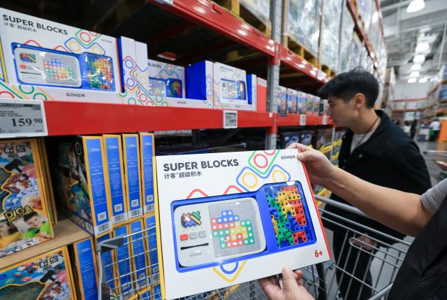 (251227) -- FOSHAN, Dec. 27, 2025 (Xinhua) -- A customer shows a Super Blocks toy produced by Giiker at a supermarket in Shenzhen, south China's Guangdong Province, Nov. 28, 2025. As traditional toys are stuck in price and homogenization competition, a batch of smart educational toys is quietly opening up new markets at home and abroad.
   In this emerging market segment, Giiker from Shunde of Foshan City, stands out. Founded in 2018, Giiker started with a Rubik's Cube product and has reached an annual gross merchandise volume of over 500 million yuan (about 71.36 million U.S. dollars) in just six years.
   Founder Su Ziming said that unlike the traditional toy industry's strategy of pursuing rapid launch and extensive distribution of new products, Giiker prefers to spend one to two years refining a product, emphasizing a long-term life cycle and high quality.
   Another outstanding company in this market segment is GANCUBE, a technology company also based in south China's Guangdong Province. It entered the market in 2014,  and has now developed into a smart competitive platform covering smart hardware, AI algorithms, and IoT ecosystem.  In the global smart competitive toy segment, GANCUBE holds approximately 20 percent of the market share. 
   Behind the rapid development lies its continuous R&D and manufacturing investment. GANCUBE has multiple production bases, including a digital factory of over 15,000 square meters. The team has a high proportion of R&D personnel, and it has even independently developed an automated cube production line that is rare in the industry. Its products are sold through platforms like Amazon and Tmall to over 100 countries and regions.
   The rise of smart educational toys reflects not only the upgrade of China's toy industry but also the evolution of educational concepts and consumption trends. As "learning through play" becomes a consensus, this market segment is attracting more and more innovators. (Xinhua/Mao Siqian)