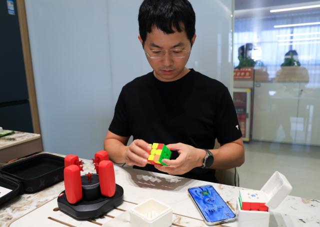 (251227) -- FOSHAN, Dec. 27, 2025 (Xinhua) -- Jiang Ganyuan, founder of the technology company GANCUBE, demonstrates the online gameplay of the smart Rubik's Cube in Shunde, Foshan City, south China's Guangdong Province, Oct. 29, 2025. As traditional toys are stuck in price and homogenization competition, a batch of smart educational toys is quietly opening up new markets at home and abroad.
   In this emerging market segment, Giiker from Shunde of Foshan City, stands out. Founded in 2018, Giiker started with a Rubik's Cube product and has reached an annual gross merchandise volume of over 500 million yuan (about 71.36 million U.S. dollars) in just six years.
   Founder Su Ziming said that unlike the traditional toy industry's strategy of pursuing rapid launch and extensive distribution of new products, Giiker prefers to spend one to two years refining a product, emphasizing a long-term life cycle and high quality.
   Another outstanding company in this market segment is GANCUBE, a technology company also based in south China's Guangdong Province. It entered the market in 2014,  and has now developed into a smart competitive platform covering smart hardware, AI algorithms, and IoT ecosystem.  In the global smart competitive toy segment, GANCUBE holds approximately 20 percent of the market share. 
   Behind the rapid development lies its continuous R&D and manufacturing investment. GANCUBE has multiple production bases, including a digital factory of over 15,000 square meters. The team has a high proportion of R&D personnel, and it has even independently developed an automated cube production line that is rare in the industry. Its products are sold through platforms like Amazon and Tmall to over 100 countries and regions.
   The rise of smart educational toys reflects not only the upgrade of China's toy industry but also the evolution of educational concepts and consumption trends. As "learning through play" becomes a consensus, this market segment is attracting more and more innovators. (Xinhua/Huo Siying)