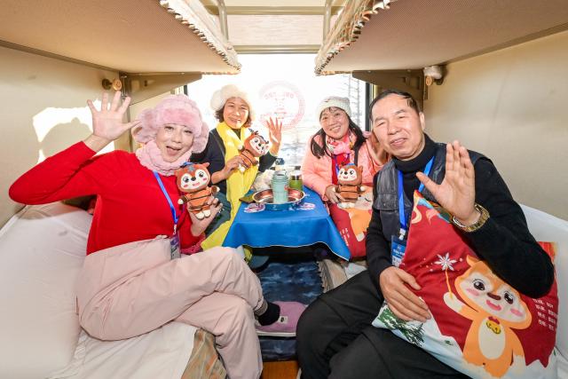 (251228) -- HARBIN, Dec. 28, 2025 (Xinhua) -- Tourists pose for photos onboard a tourism train in northeast China's Heilongjiang Province, on Dec. 28, 2025. Train Y999/998, an ice-and-snow themed tourism loop train, started a six-day trip on Sunday. (Photo by Yuan Yong/Xinhua)