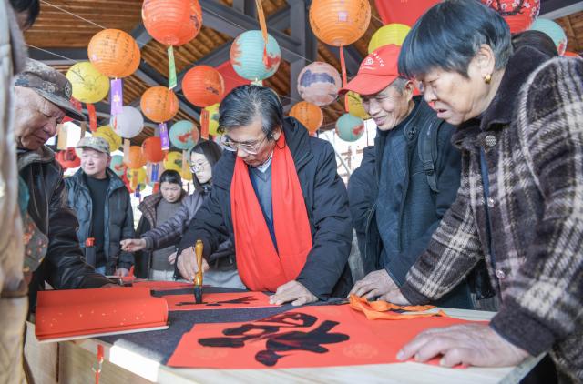 (251228) -- CIXI, Dec. 28, 2025 (Xinhua) -- A calligraphy enthusiast writes for visitors during a folk culture fair in Cixi, east China's Zhejiang Province, Dec. 28, 2025. (Xinhua/Xu Yu)