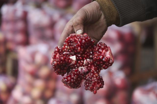 (251228) -- KABUL, Dec. 28, 2025 (Xinhua) -- A retailer displays a pomegranate in Kabul, Afghanistan, on Dec. 28, 2025. Afghanistan has exported pomegranates from Kandahar province to Qatar for the first time, as a significant step in efforts to expand the country's agricultural products to new international markets, local media Tolo news reported Saturday. (Photo by Saifurahman Safi/Xinhua)