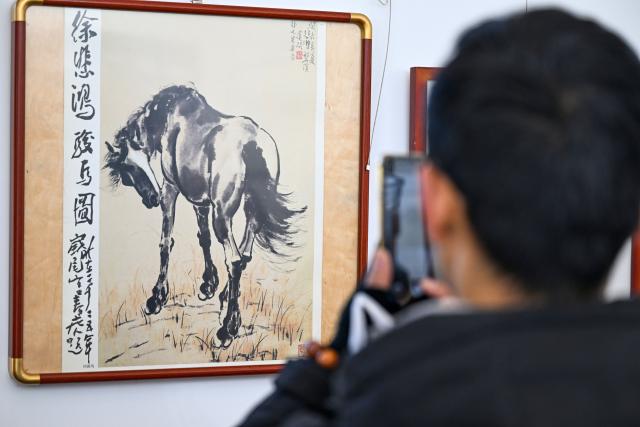 (251229) -- BEIJING, Dec. 29, 2025 (Xinhua) -- A visitor views a horse painting at an exhibition in north China's Tianjin, Dec. 29, 2025. Various activities are held across China to celebrate the upcoming new year. (Xinhua/Zhao Zishuo)