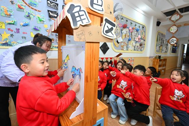 (251229) -- BEIJING, Dec. 29, 2025 (Xinhua) -- A child tries shadow puppetry in a kindergarten in Xiangyang City, central China's Hubei Province, Dec. 29, 2025. Various activities are held across China to celebrate the upcoming new year. (Photo by Li Xuhui/Xinhua)