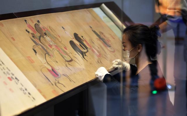 (251229) -- SHENYANG, Dec. 29, 2025 (Xinhua) -- Staff members prepare a Song Dynasty (960-1279 AD) replica of the painting "Lady Guoguo's Spring Outing" for exhibition at Liaoning Provincial Museum in Shenyang, northeast China's Liaoning Province, Dec. 29, 2025. The painting, attributed to Tang Dynasty (618-907 AD) court painter Zhang Xuan, is one of the figure painting masterpieces depicting aristocratic women. The work will be on display at Liaoning Provincial Museum from Dec. 30, 2025 to March 29, 2026. (Xinhua/Li Gang)