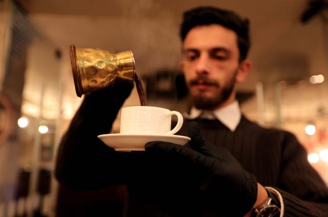 (251229) -- AMMAN, Dec. 29, 2025 (Xinhua) -- A man pours Arabic coffee at a cafe in Amman, Jordan, Dec. 24, 2025. TO GO with "Feature: From social occasions to daily habits, coffee craze reveals changing Jordanian lifestyle" (Photo by Mohammad Abu Ghosh/Xinhua)