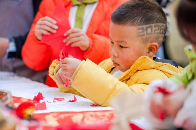 (251230) -- BEIJING, Dec. 30, 2025 (Xinhua) -- A child makes a paper-cut window decoration in a community in Wenzhou City, east China's Zhejiang Province, Dec. 28, 2025. Various activities were held across China to celebrate the upcoming new year. (Photo by Liu Jili/Xinhua)