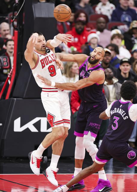 (251230) -- CHICAGO, Dec. 30, 2025 (Xinhua) -- Chicago Bulls' Nikola Vucevic (L) throws a pass against Minnesota Timberwolves' Rudy Gobert during the 2025-2026 NBA regular season basketball game between Minnesota Timberwolves and Chicago Bulls in Chicago, the United States, Dec. 29, 2025. (Photo by Joel Lerner/Xinhua)