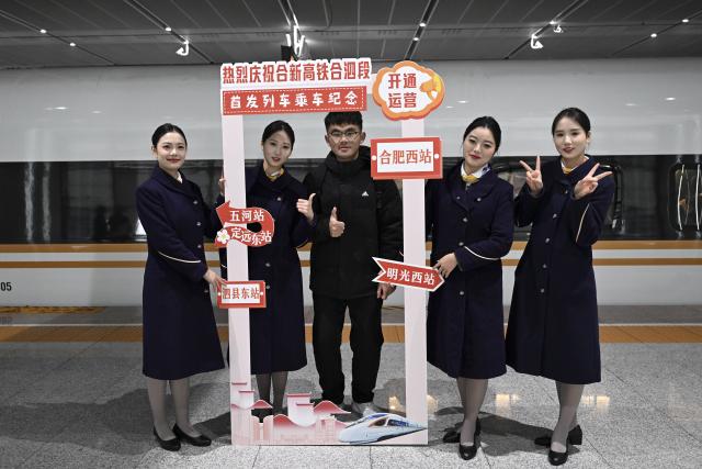 (251230) -- HEFEI, Dec. 30, 2025 (Xinhua) -- A passenger and train attendants pose for a group photo beside G9500, the first train of a newly-opened section of the Hefei-Xinyi high-speed railway, in the Hefei West Railway Station in Hefei City, capital of east China's Anhui Province, Dec. 30, 2025.
  The Hefei-Sixian section of the Hefei-Xinyi high-speed railway was officially put into operation on Tuesday, marking the opening of another fast passenger line between Hefei City and eastern Anhui Province.
  The Hefei-Xinyi high-speed railway starts from Hefei West Railway Station in Hefei, and terminates at Xinyi East Railway Station in Xinyi City of Jiangsu Province. Spanning approximately 335 kilometers and with a design speed of 350 kilometers per hour, the railway is being constructed in phases. 
  The newly-opened section of the railway stretches 198 kilometers, setting five newly-built stations, namely Hefei West, Dingyuan East, Mingguang West, Wuhe, and Sixian East railway stations. (Xinhua/Huang Bohan)