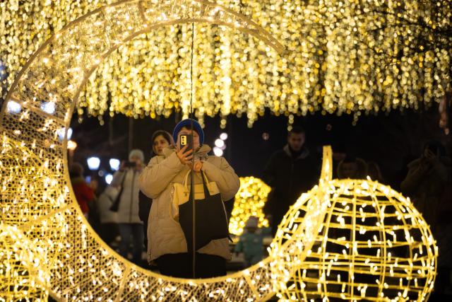 (251230) -- VLADIVOSTOK, Dec. 30, 2025 (Xinhua) -- A pedestrian takes photos among New Year's lighting installations in Russian Far East city of Vladivostok, Dec. 29, 2025. (Photo by Andrey Matveenko/Xinhua)