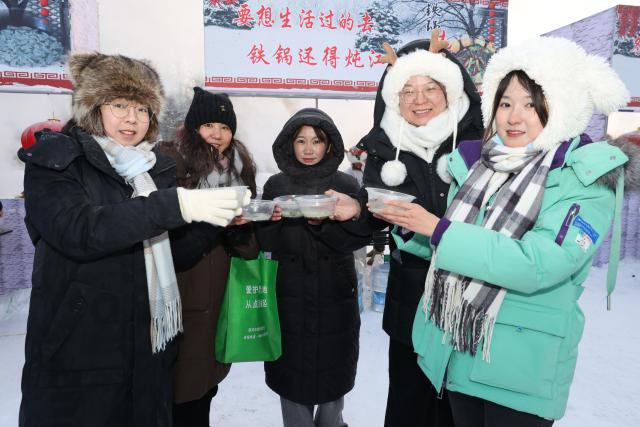 (251230) -- MOHE, Dec. 30, 2025 (Xinhua) -- Tourists pose for photos with bowls of fish soup during a winter fishing event in Mohe, northeast China's Heilongjiang Province, Dec. 30, 2025. The event held on Tuesday showcased some customs and folk arts only found in Mohe. (Photo by Shao Tianli/Xinhua)