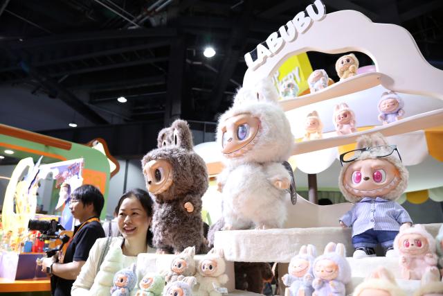 (251230) -- BEIJING, Dec. 30, 2025 (Xinhua) -- A participant poses for photos at the booth of Pop Mart during the 2025 China International Fair for Trade in Services (CIFTIS) in Beijing, capital of China, Sept. 10, 2025. (Xinhua/Hou Jun)