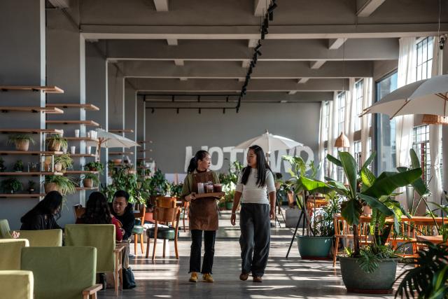(251231) -- JINGHONG, Dec. 31, 2025 (Xinhua) -- Wei Chun (1st R) talks to a staff member at a studio in Dadugang Township of Jinghong City, Xishuangbanna Dai Autonomous Prefecture, southwest China's Yunnan Province, Dec. 20, 2025. Wei Chun used to work at an international hotel in a first-tier city. In June 2024, she became an agricultural manager of a collective economy company in Dadugang Township, a role locals refer to as the "Village CEO." 
   Under her leadership, idle factory buildings and vacant land were transformed into cafes, educational spaces, and campsites, providing recreational spaces for visitors. Wei also offered free training in coffee making, tea art, and rural hospitality management, improving service quality and expanding employment opportunities for villagers.
   By 2025, Wei has helped more than 100 villagers acquire new skills and attracted nine talents returning home to start businesses here. (Xinhua/Hu Chao)