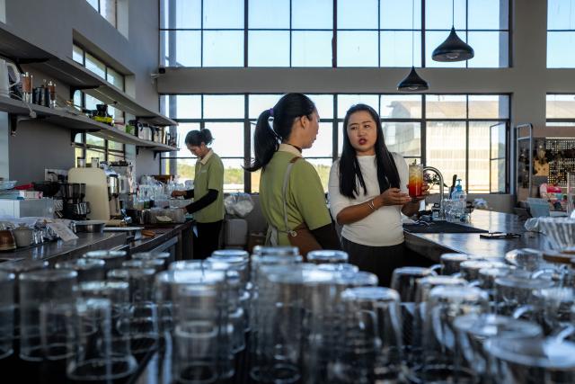 (251231) -- JINGHONG, Dec. 31, 2025 (Xinhua) -- Wei Chun (R) instructs a staff member on making tea drinks at a studio in Dadugang Township of Jinghong City, Xishuangbanna Dai Autonomous Prefecture, southwest China's Yunnan Province, Dec. 20, 2025. Wei Chun used to work at an international hotel in a first-tier city. In June 2024, she became an agricultural manager of a collective economy company in Dadugang Township, a role locals refer to as the "Village CEO." 
   Under her leadership, idle factory buildings and vacant land were transformed into cafes, educational spaces, and campsites, providing recreational spaces for visitors. Wei also offered free training in coffee making, tea art, and rural hospitality management, improving service quality and expanding employment opportunities for villagers.
   By 2025, Wei has helped more than 100 villagers acquire new skills and attracted nine talents returning home to start businesses here. (Xinhua/Hu Chao)