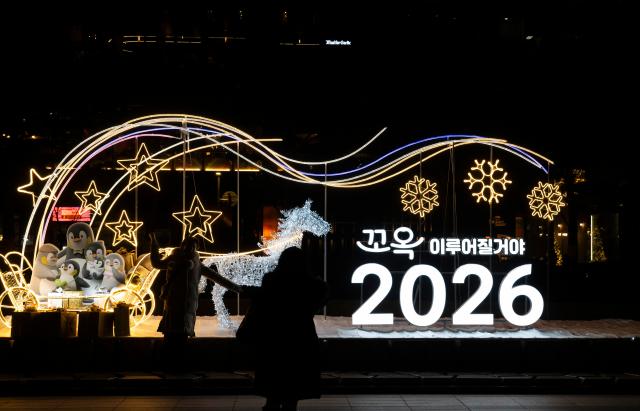 (251231) -- SEOUL, Dec. 31, 2025 (Xinhua) -- A woman poses for a photo in front of a New Year light display in Seoul, South Korea on Dec. 31, 2025. (Photo by Jun Hyosang/Xinhua)