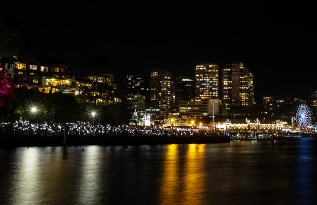 (251231) -- SYDNEY, Dec. 31, 2025 (Xinhua) -- Participants observe a moment of silence at the Harbour Bridge in Sydney, Australia, Dec. 31, 2025. A moment of silence was observed during a fireworks show, with the Harbour Bridge lit in white, to commemorate the victims of a mass shooting at Sydney's Bondi Beach. (Xinhua/Ma Ping)