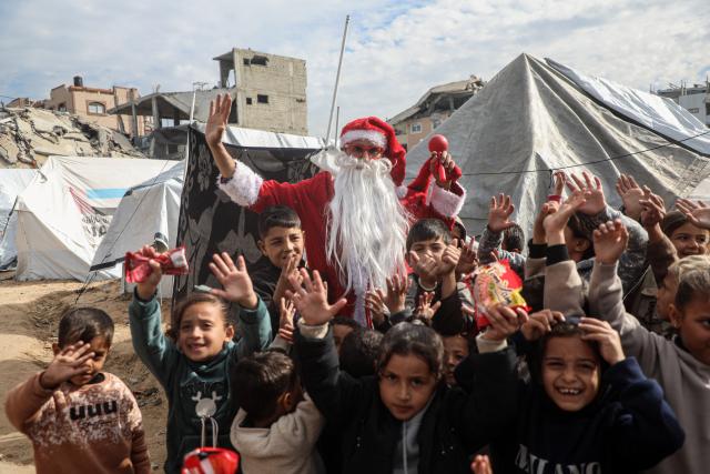 (260101) -- GAZA, Jan. 1, 2026 (Xinhua) -- A young Palestinian man dressed as Santa Claus distributes sweets to displaced children ahead of the New Year at a temporary shelter in the Sheikh Radwan neighborhood, northwest of Gaza City, on Dec. 31, 2025. (Photo by Rizek Abdeljawad/Xinhua)