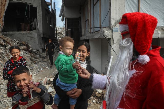 (260101) -- GAZA, Jan. 1, 2026 (Xinhua) -- A young Palestinian man dressed as Santa Claus distributes sweets to displaced children ahead of the New Year at a temporary shelter in the Sheikh Radwan neighborhood, northwest of Gaza City, on Dec. 31, 2025. (Photo by Rizek Abdeljawad/Xinhua)