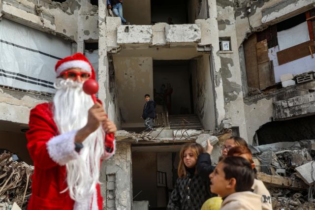 (260101) -- GAZA, Jan. 1, 2026 (Xinhua) -- A young Palestinian man dressed as Santa Claus distributes sweets to displaced children ahead of the New Year at a temporary shelter in the Sheikh Radwan neighborhood, northwest of Gaza City, on Dec. 31, 2025. (Photo by Rizek Abdeljawad/Xinhua)