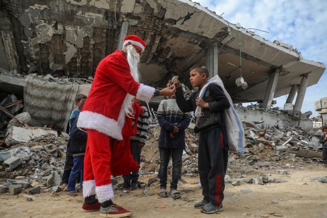 (260101) -- GAZA, Jan. 1, 2026 (Xinhua) -- A young Palestinian man dressed as Santa Claus distributes sweets to displaced children ahead of the New Year at a temporary shelter in the Sheikh Radwan neighborhood, northwest of Gaza City, on Dec. 31, 2025. (Photo by Rizek Abdeljawad/Xinhua)