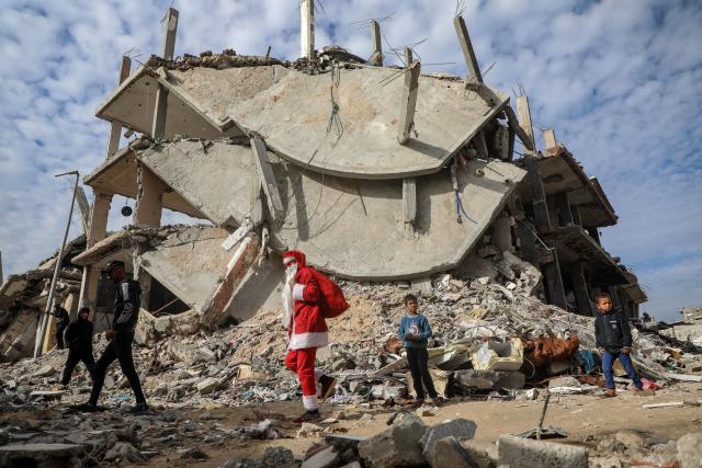 (260101) -- GAZA, Jan. 1, 2026 (Xinhua) -- A young Palestinian man dressed as Santa Claus distributes sweets to displaced children ahead of the New Year at a temporary shelter in the Sheikh Radwan neighborhood, northwest of Gaza City, on Dec. 31, 2025. (Photo by Rizek Abdeljawad/Xinhua)