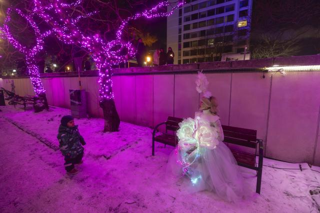 (260101) -- ESPOO, Jan. 1, 2026 (Xinhua) -- A woman in illuminated costume interacts with a child during a New Year's Eve light show in Espoo, a city in southern Finland, Dec. 31, 2025. (Photo by Matti Matikainen/Xinhua)