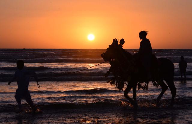 (260101) -- KARACHI, Jan. 1, 2026 (Xinhua) -- This photo taken on Dec. 31, 2025 shows the silhouette of tourists enjoying horse ride at the beach during the last sunset of the year 2025 in southern Pakistan's Karachi. (Str/Xinhua)