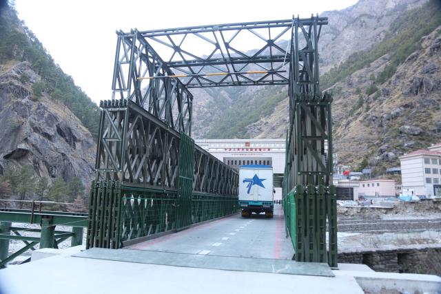 (260101) -- BEIJING, Jan. 1, 2026 (Xinhua) -- A photo taken from the Rasuwa Port in Nepal on Jan. 1, 2026 shows a truck running on a steel temporary access bridge to go through the Gyirong Port in southwest China's Xizang Autonomous Region. China-Nepal Gyirong-Rasuwa Port, one of the largest land ports between the two countries, resumed customs and passenger clearance on Thursday morning, nearly six months after the area was struck by flood. (Xinhua/Zhang Ping)