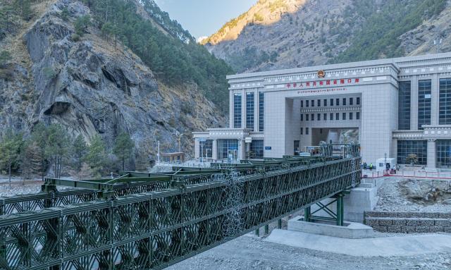 (260101) -- BEIJING, Jan. 1, 2026 (Xinhua) -- A drone photo taken on Jan. 1, 2026 shows a steel temporary access bridge and the Gyirong Port in southwest China's Xizang Autonomous Region. China-Nepal Gyirong-Rasuwa Port, one of the largest land ports between the two countries, resumed customs and passenger clearance on Thursday morning, nearly six months after the area was struck by flood. (Xinhua/Tenzin Nyida)