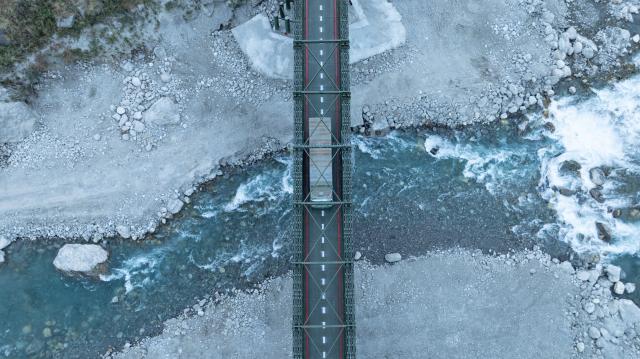 (260101) -- BEIJING, Jan. 1, 2026 (Xinhua) -- An aerial drone photo taken on Jan. 1, 2026 shows a truck from Nepal running on a steel temporary access bridge to go through the Gyirong Port in southwest China's Xizang Autonomous Region. China-Nepal Gyirong-Rasuwa Port, one of the largest land ports between the two countries, resumed customs and passenger clearance on Thursday morning, nearly six months after the area was struck by flood. (Xinhua/Tenzin Nyida)