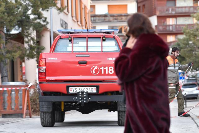 (260101) -- CRANS-MONTANA, Jan. 1, 2026 (Xinhua) -- A woman walks past a fire truck at the scene of a fire at a bar in the Crans-Montana ski resort in Valais Canton of southwestern Switzerland, Jan. 1, 2026. Around 40 people died and over 110 others were injured after a fire broke out at a bar in the Crans-Montana ski resort, local police said on Thursday. (Xinhua/Lian Yi)