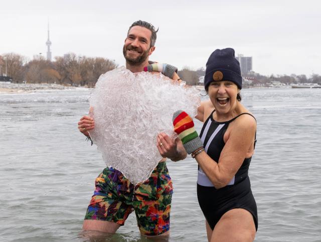 (260102) -- TORONTO, Jan. 2, 2026 (Xinhua) -- Participants pose for photos with a piece of floating ice in Lake Ontario during the Toronto Polar Bear Dip event in Toronto, Canada, on Jan. 1, 2026. Hundreds of people braved the chilly waters here on Thursday to celebrate the first day of 2026 and raise funds for charity. (Photo by Zou Zheng/Xinhua)